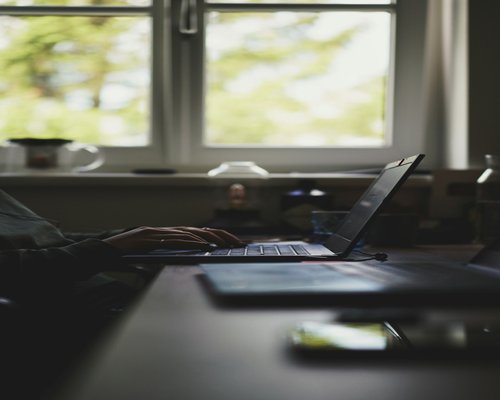 Person working on a laptop at home with natural light from a window