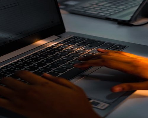 Detail of hands typing on a laptop keyboard with soft office lighting